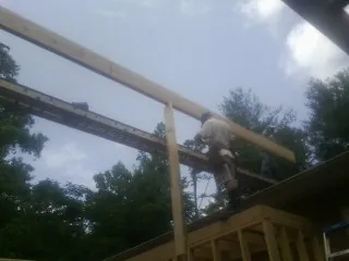 Carpenter setting a ridge beam over a new addition frame — Ice Dam Removal by Roofing Brothers in Spruce Creek