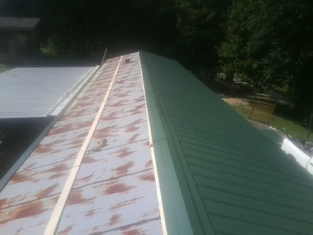 Old rusted panels beside newly installed green metal roofing — Wind Damage Roof Repair by Roofing Brothers in Spruce Creek