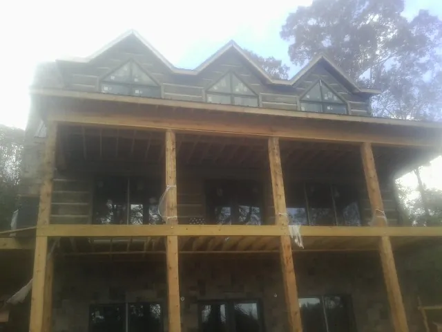 Dormers and porch framing on a large log home under construction — Roof Coating work by our crew in Spruce Creek
