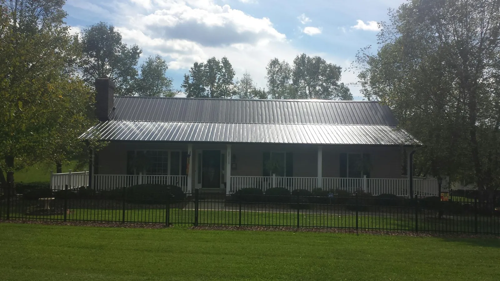 Gray metal roof on a brick ranch with a full width front porch — Gutter Guard Installation work by our crew in Spruce Creek