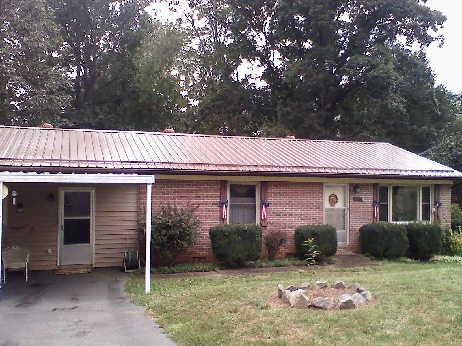 Bronze metal roof and carport on a brick ranch home — Roof Repair work by our crew in Spruce Creek