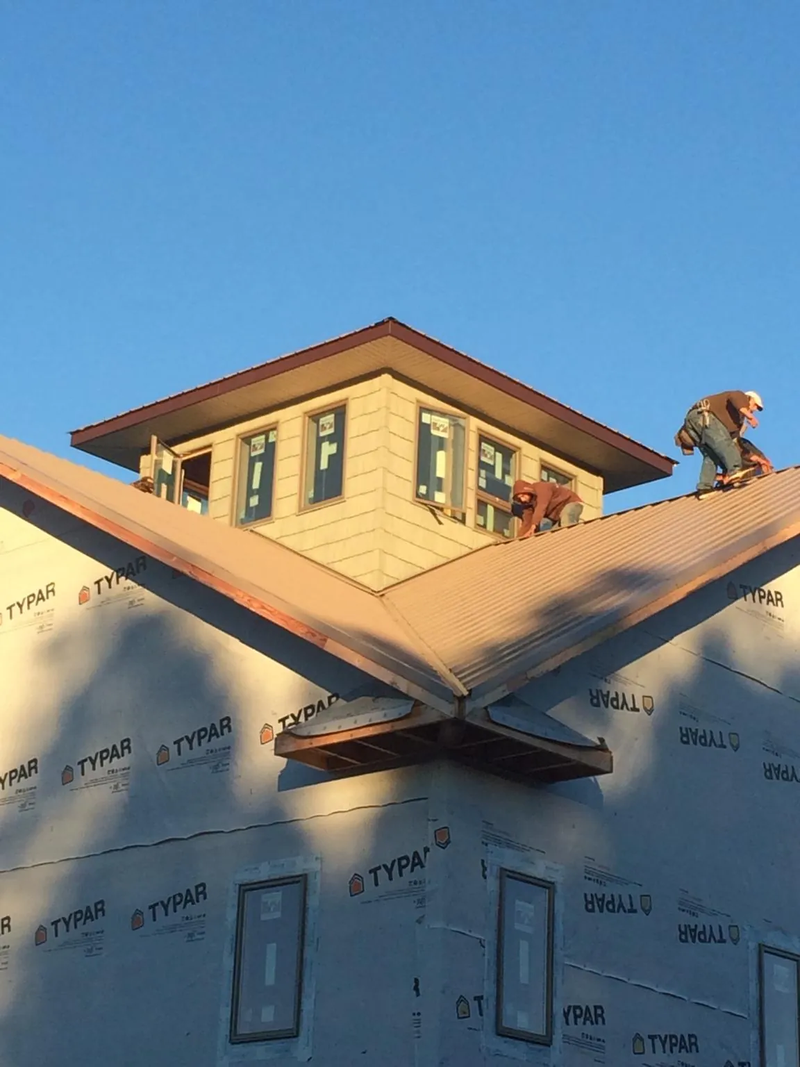 Roofers working around a rooftop cupola on a new metal roof at sunset — Roof Waterproofing in Spruce Creek by Roofing Brothers